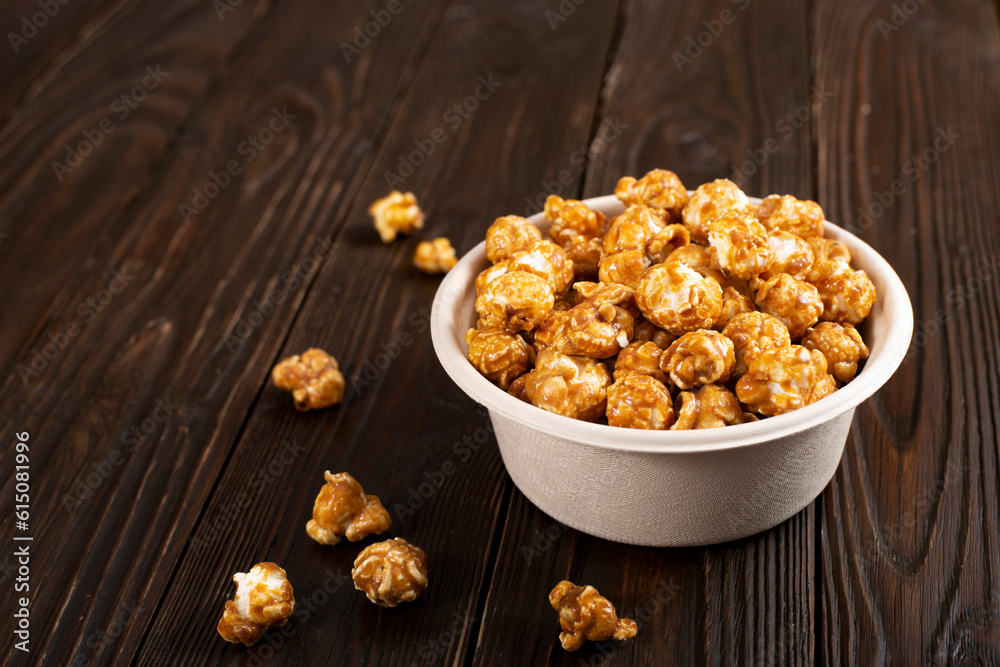 Caramelized popcorn in paper bucket on wooden kitchen table