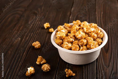 Caramelized popcorn in paper bucket on wooden kitchen table