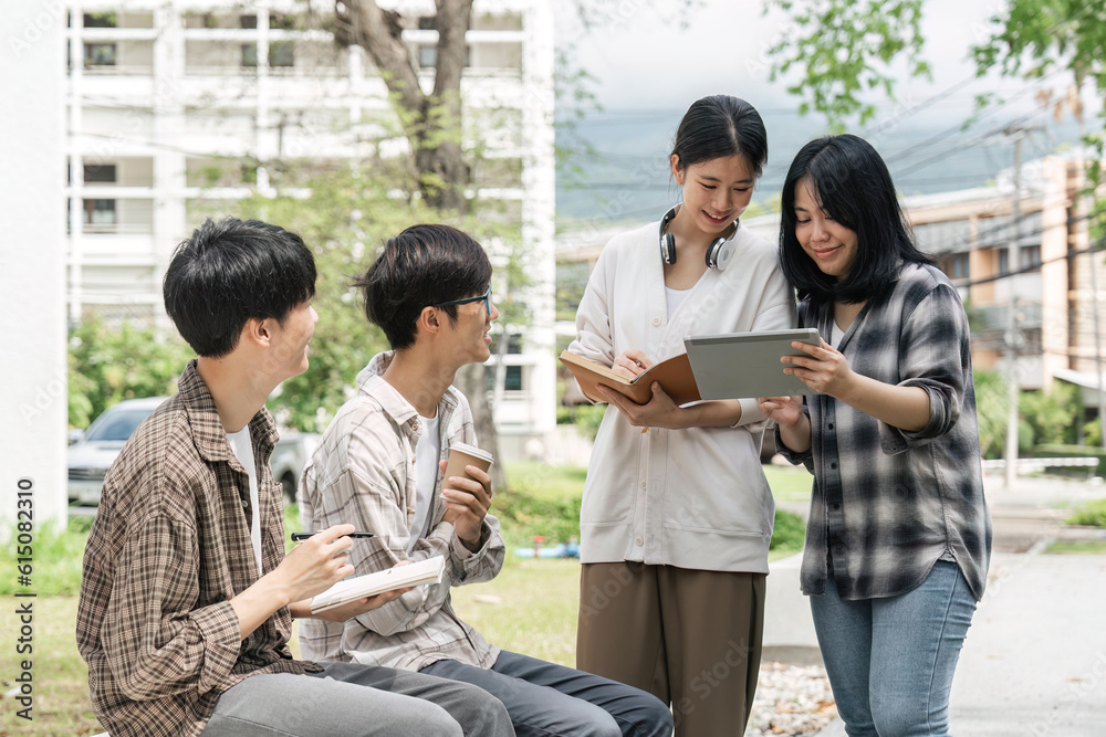 University students sitting together at table with books and laptop and tablet. Happy young people doing group study in university University students sitting together at table with books and laptop and tablet. Happy young people doing group study in university