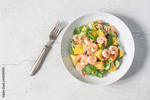Healthy food shrimp salad has mango cucumber peppermint in bowl on slate background.