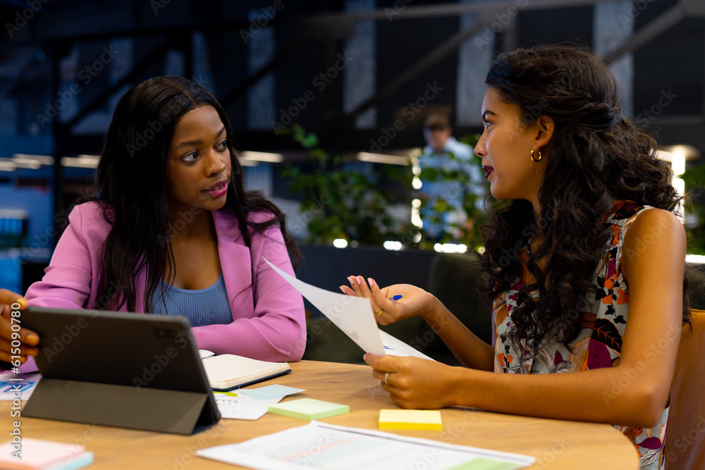 Diverse female colleagues in discussion using tablet in casual office meeting Diverse female colleagues in discussion using tablet in casual office meeting