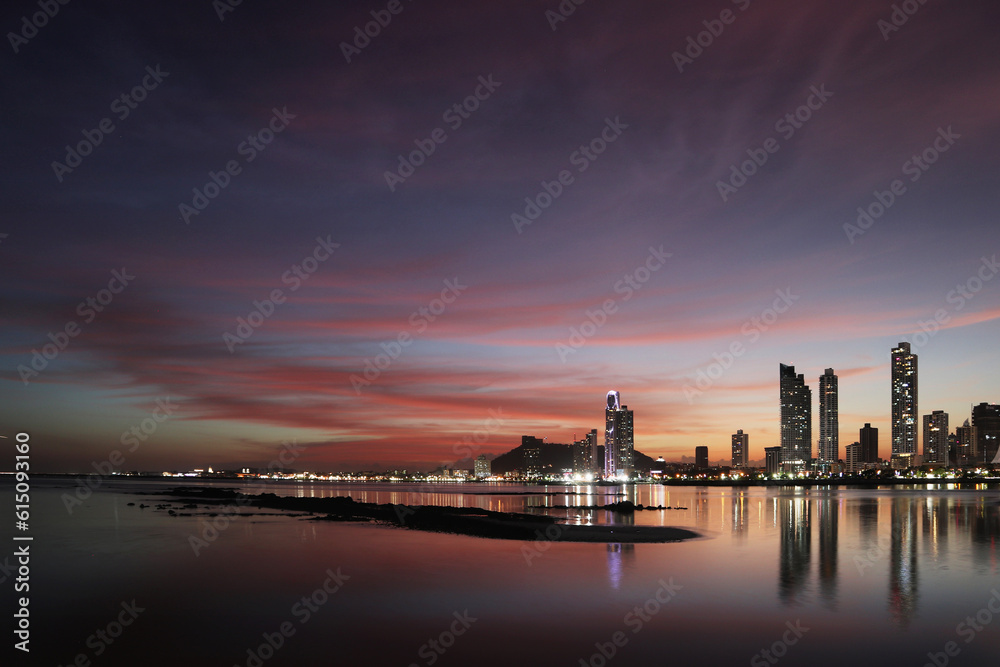 sunset over Panama city with reflection of the skyline on the bay's ocean water with dramatic red clouds 