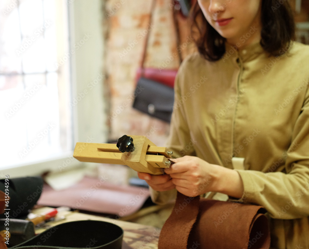 young brunette woman works in a bag making studio, cuts out details
