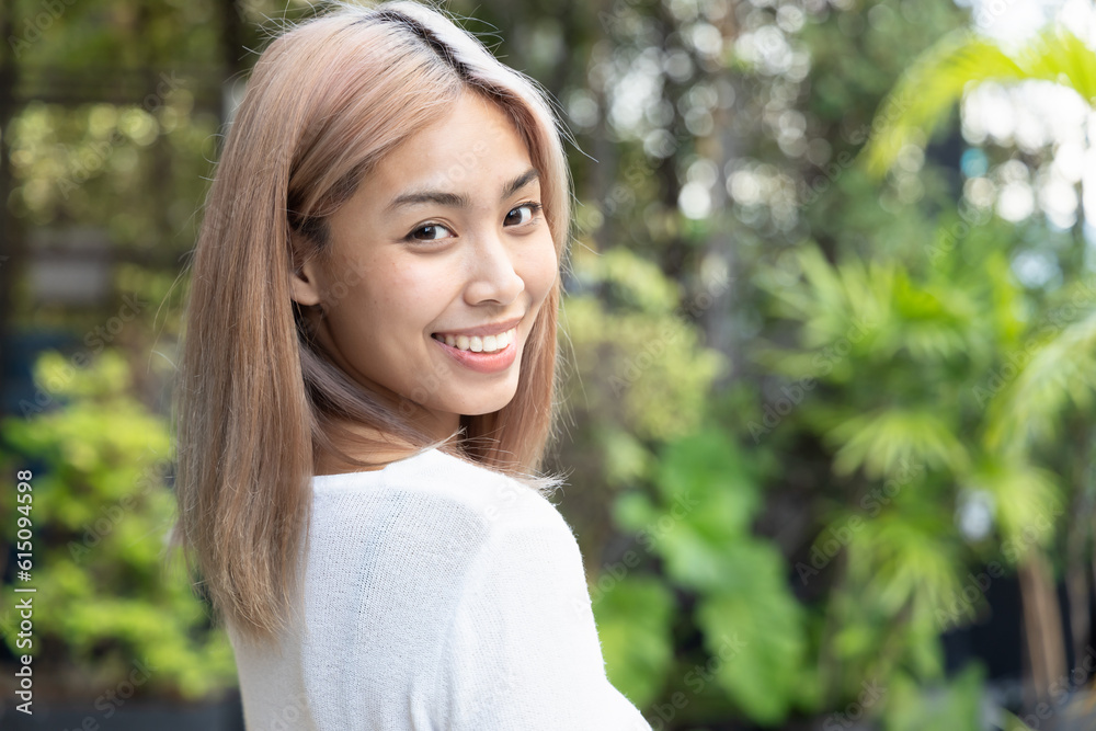 Happy smiling southeast asian woman with modern hair coloring looking back