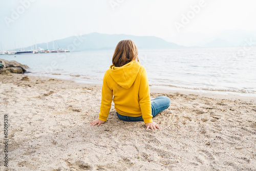 Lonely beautiful sad girl teenager sits thoughtfully on sand sea beach. Dreams,anxiety,worries about future,school friends, parents. Teen bullying, psychological problems in adolescent puberty period