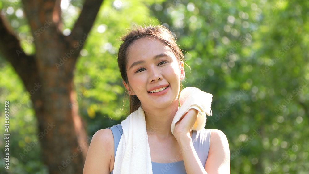 Portrait young asian woman attractive smiling and use white towel resting after workout. Smiling sporty young woman working out outdoors and looking at camera. Healthy lifestyle well being wellness