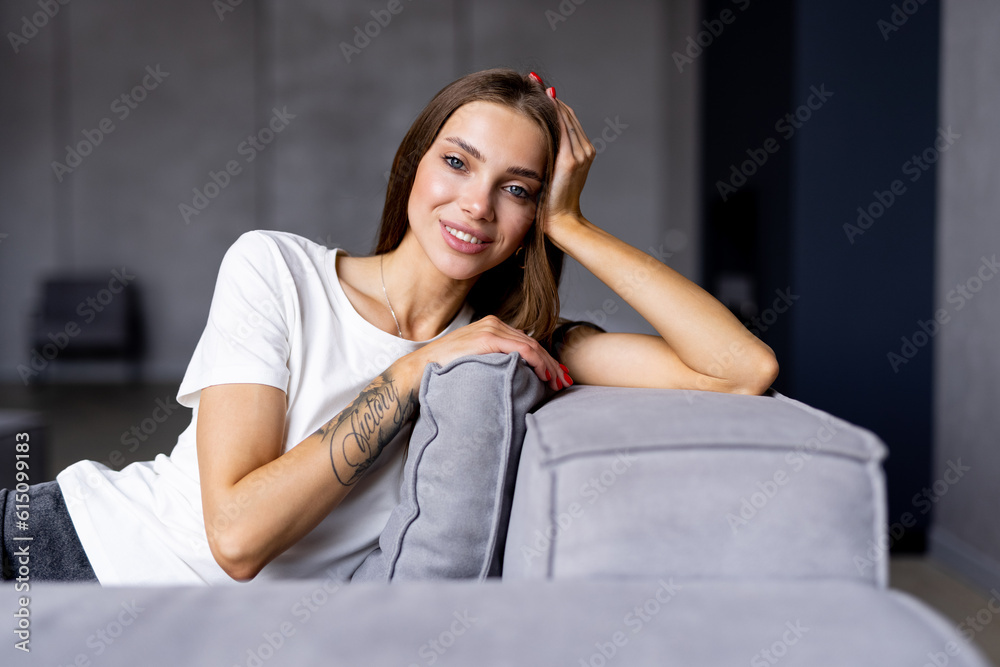 Smiling young woman wearing casual clothes relaxing on a couch at home Smiling young woman wearing casual clothes relaxing on a couch at home