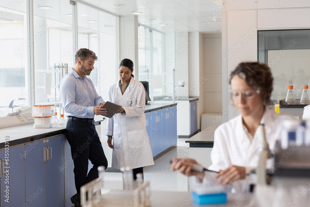 Scientists discussing data using a digital tablet in a laboratory Scientists discussing data using a digital tablet in a laboratory