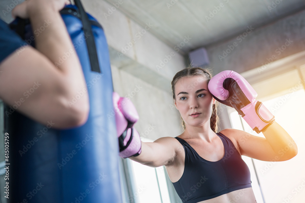 Handsome man beautiful sportswoman in boxing gloves punching bags exercise in fitness gym