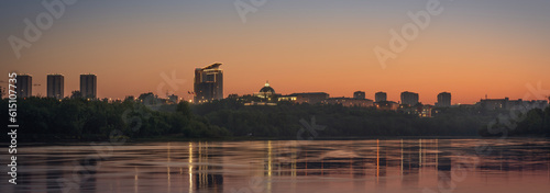 Evening city by the river - panorama. Orange sunrise or sunset over the city.