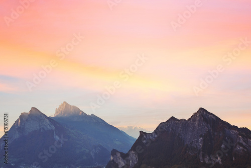Silhouette of mountain at sunset pastel orange, pink, blue sky and clouds.
