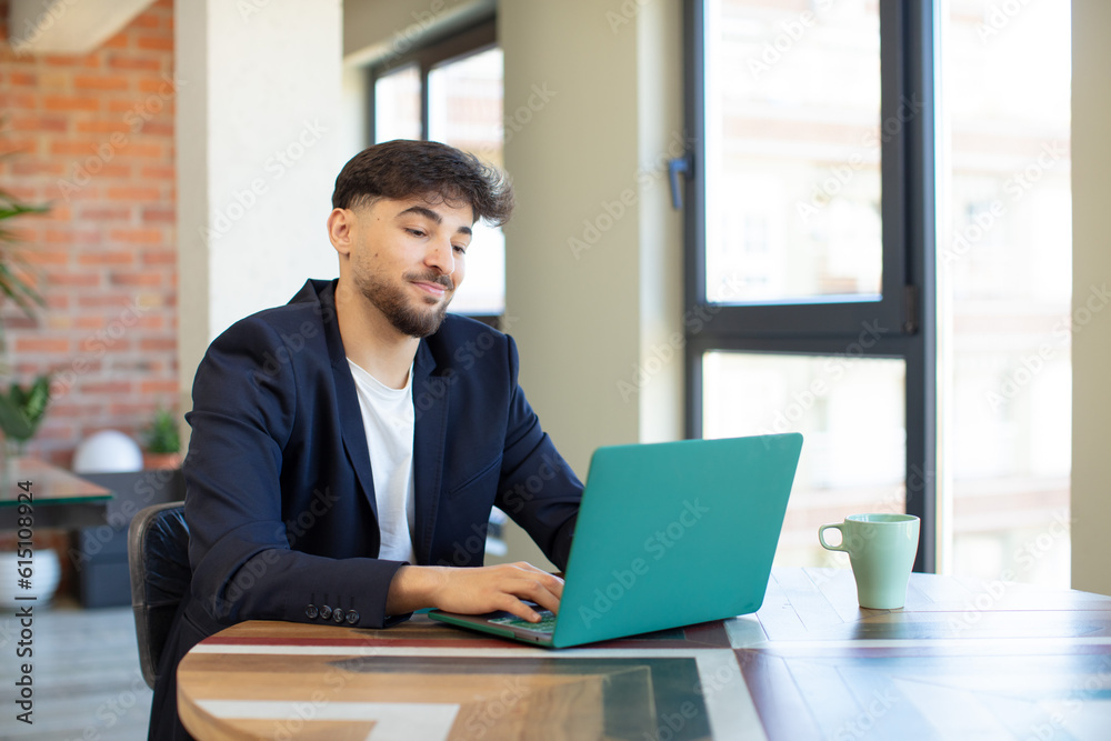 young handsome man smiling and looking with a happy confident expression. freelance concept with laptop young handsome man smiling and looking with a happy confident expression. freelance concept with laptop