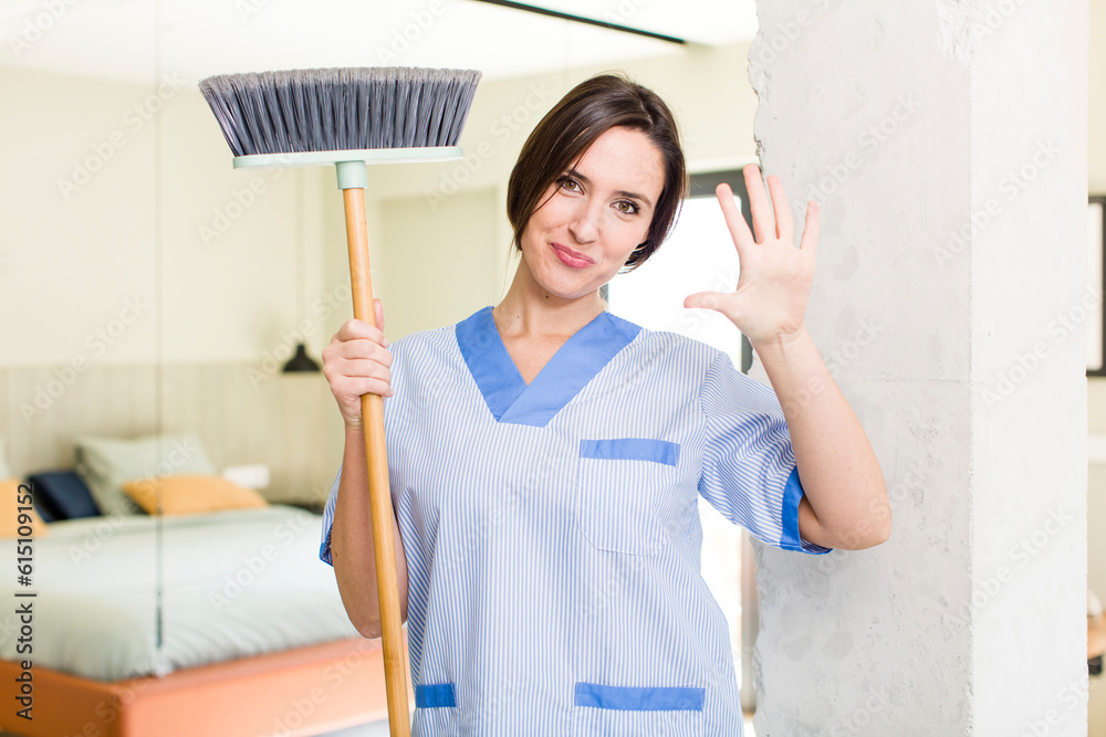 young pretty woman smiling and looking friendly, showing number five. housekeeper concept young pretty woman smiling and looking friendly, showing number five. housekeeper concept