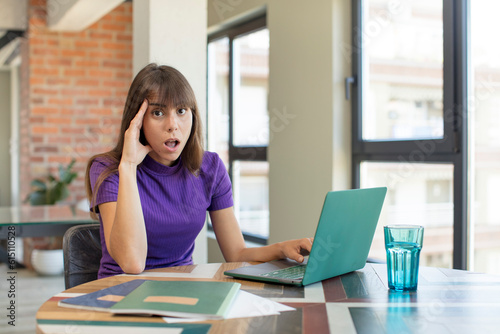 young pretty woman looking happy, astonished and surprised. universitary student with a laptop