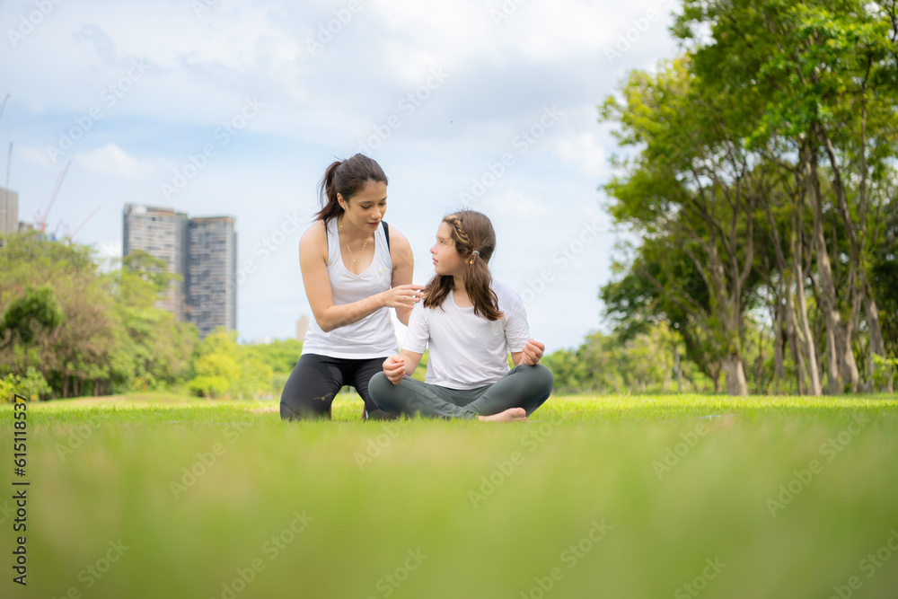 Young female and little girl with outdoor activities in the city park, Yoga is her chosen activity.