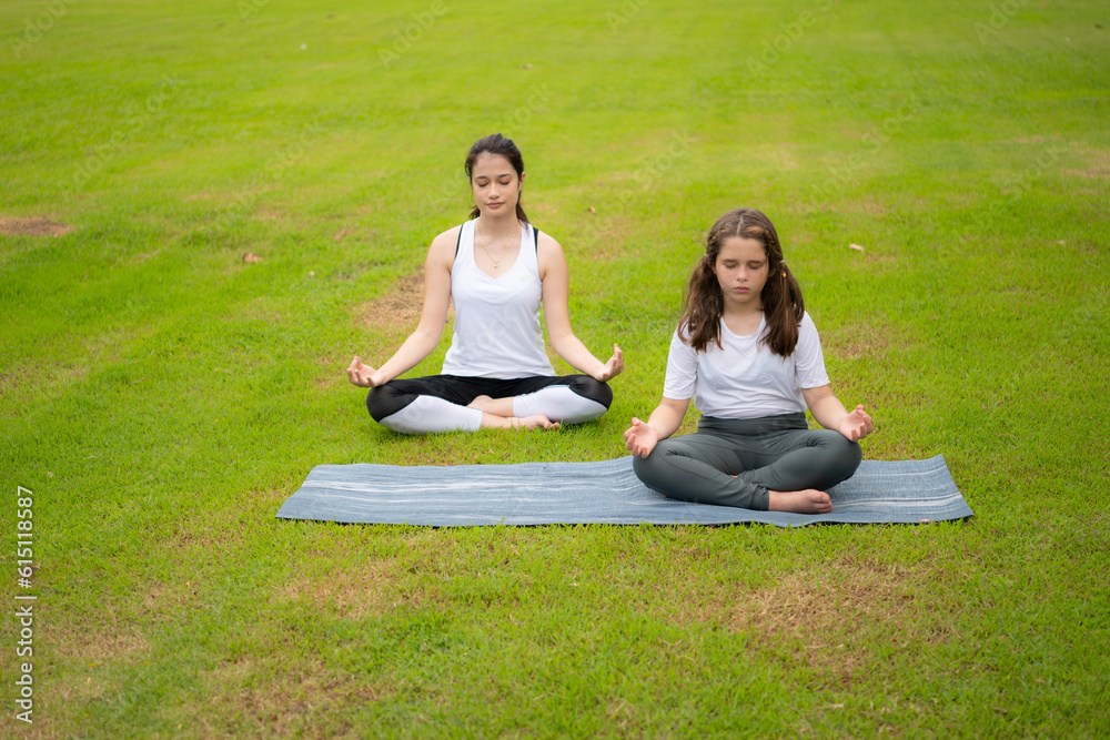 Young female and little girl with outdoor activities in the city park, Yoga is her chosen activity.
