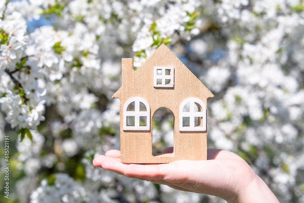 The girl holds the house symbol against the background of blossoming cherry
The girl holds the house symbol against the background of blossoming cherry