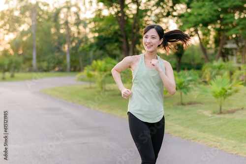 Fit Asian young woman jogging in park smiling happy running and enjoying a healthy outdoor lifestyle. Female jogger. Fitness runner girl in public park. healthy lifestyle and wellness being concept