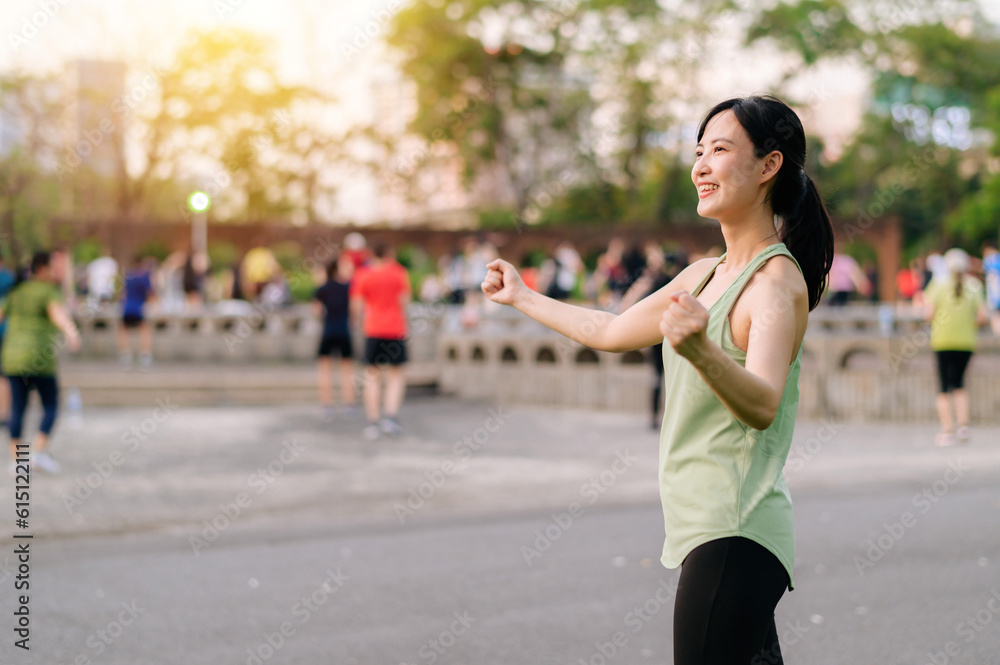 Female jogger. Fit young Asian woman with green sportswear aerobics dance exercise in park and enjoying a healthy outdoor. Fitness runner girl in public park. Wellness being concept