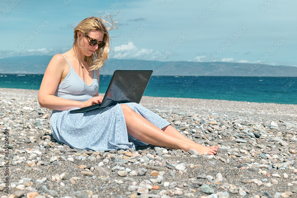 Blond pretty woman using laptop on the beach. Businesswoman working outdoors. Technology and travel, freelance concept. Modern office. Distant work.
