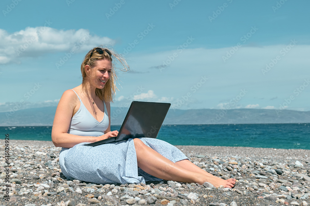 Blond pretty woman using laptop on the beach. Businesswoman working outdoors. Technology and travel, freelance concept. Modern office. Distant work.