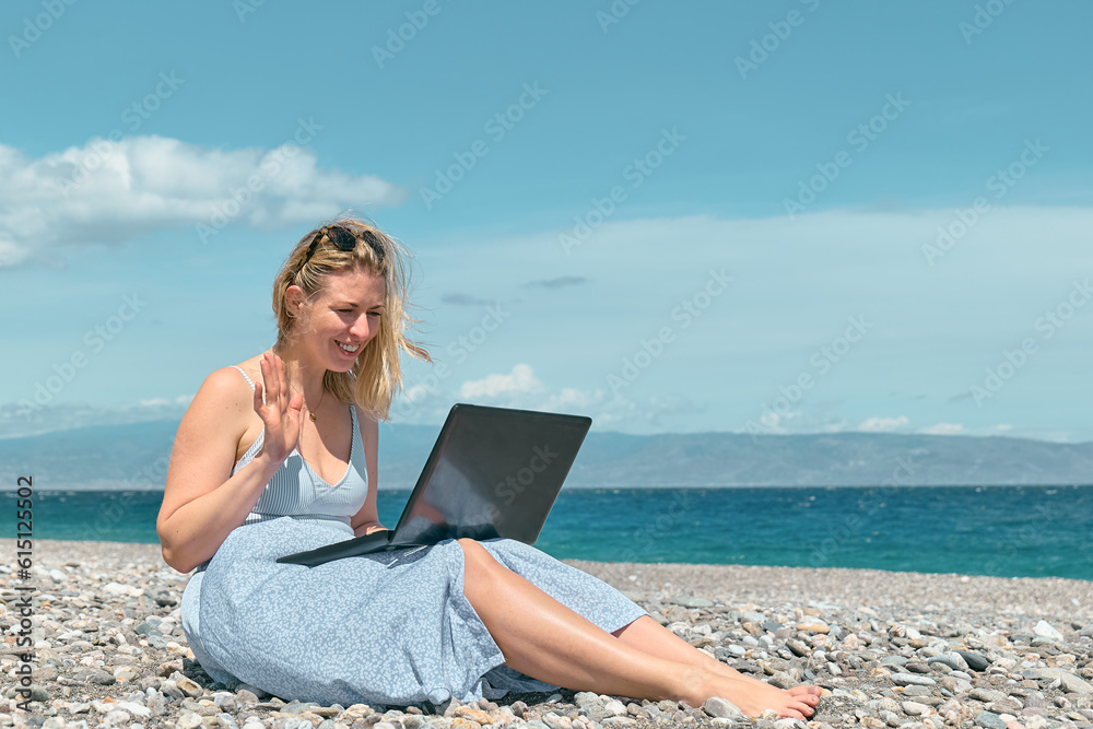 Blond pretty woman using laptop for video call on the beach. Businesswoman working outdoors. Technology and travel, freelance concept. Modern office. Distant work.