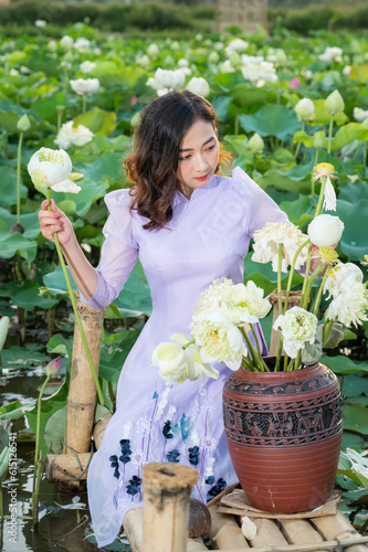 Vietnamese woman wearing traditional dress (ao dai) in a lotus flower pond photo