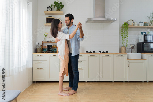 Beautiful young couple dancing in kitchen at home. Happy loving young couple dancing on date in modern kitchen smiling husband and wife © jittawit.21