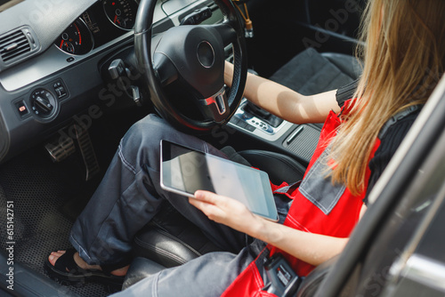 Woman Worker Using Digital Tablet With Empty Screen Sitting In Car doing On-board Diagnostics.