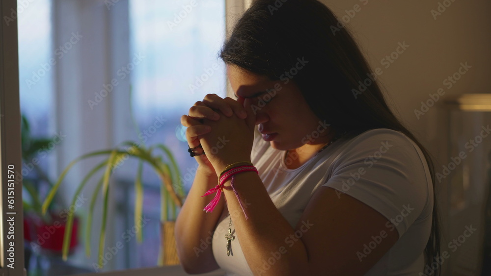 Φωτογραφία Religious adult girl in 20s Praying to God, Hands Clenched during Sunset at Home