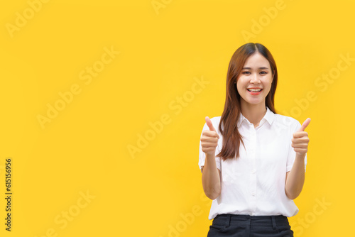 Women doing thumbs up gesture with both hands while happiness smiling on isolated yellow background