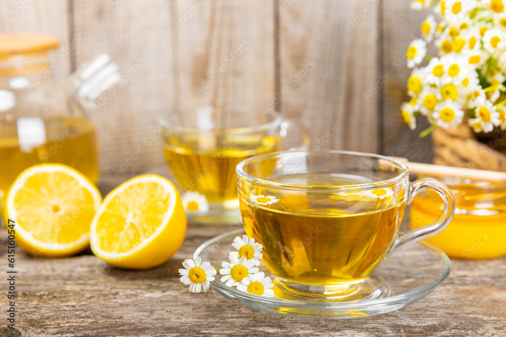 Chamomile herbal tea in a glass cup on a brown wooden table with honey, lemon and chamomile bouquet. Close-up. Copy space. healthy herbal drinks, immunity tea. Natural healer concept.Place for text. Chamomile herbal tea in a glass cup on a brown wooden table with honey, lemon and chamomile bouquet. Close-up. Copy space. healthy herbal drinks, immunity tea. Natural healer concept.Place for text.