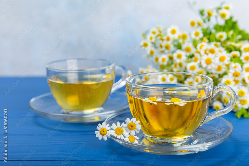 Chamomile herbal tea in a cup on a blue wooden table with honey, lemon and chamomile bouquet. Close-up. Copy space. healthy herbal drinks, immunity tea. Natural healer concept.Place for text. Chamomile herbal tea in a cup on a blue wooden table with honey, lemon and chamomile bouquet. Close-up. Copy space. healthy herbal drinks, immunity tea. Natural healer concept.Place for text.