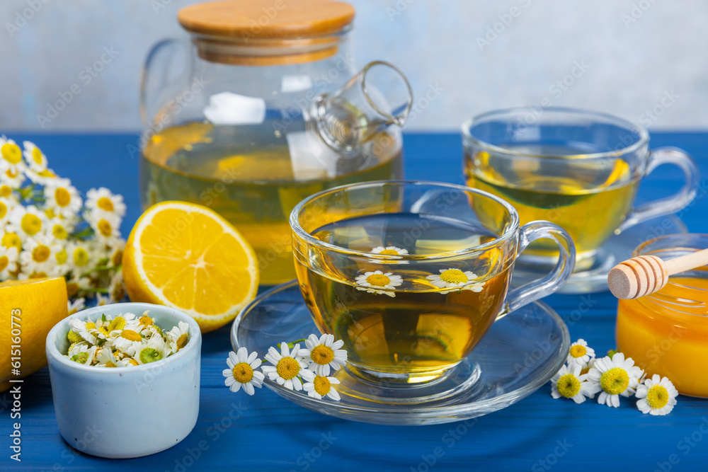 Chamomile herbal tea in a cup on a blue wooden table with honey, lemon and chamomile bouquet. Close-up. Copy space. healthy herbal drinks, immunity tea. Natural healer concept.Place for text. Chamomile herbal tea in a cup on a blue wooden table with honey, lemon and chamomile bouquet. Close-up. Copy space. healthy herbal drinks, immunity tea. Natural healer concept.Place for text.