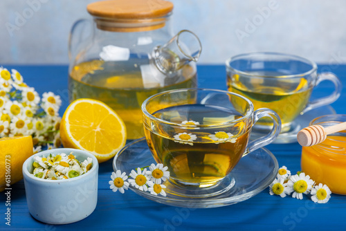 Chamomile herbal tea in a cup on a blue wooden table with honey, lemon and chamomile bouquet. Close-up. Copy space. healthy herbal drinks, immunity tea. Natural healer concept.Place for text.