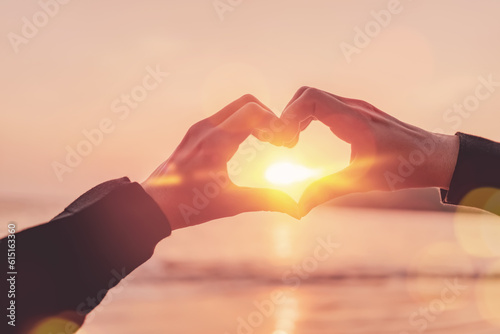 Female hands heart shape on nature bokeh sun light wave and blur tropical sunset beach abstract background. Copy space of happy love travel and freedom in nature concept. Vintage color style.