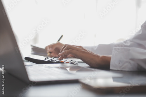 Close up Business woman using calculator and laptop for do math finance on wooden desk, tax, accounting, statistics and analytical research concept photo