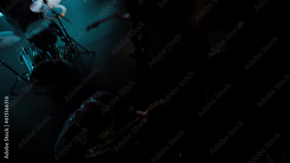 Jib shot of a rock band playing the gig during concert on stage of a large venue, surrounded by bright flashing stage lights