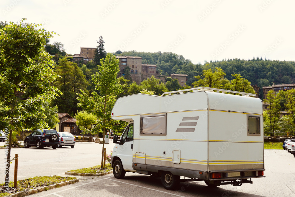 White motorhome parked in Rupit, Osona. Stone houses on top of the green mountain. Family trip to villages in Catalunya.