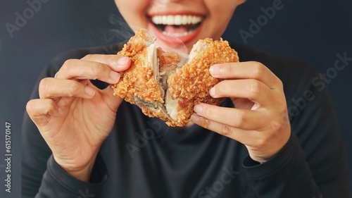 Cheerful people holding fried chicken standing over dark background with copy space.