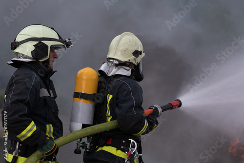 Firefighters using water fog type fire extinguisher to fighting with the fire flame to control fire not to spreading out. Firefighter industrial and public safety concept. 