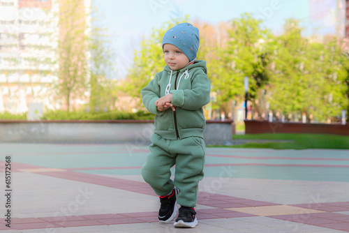 A boy in a green suit walks in a city park