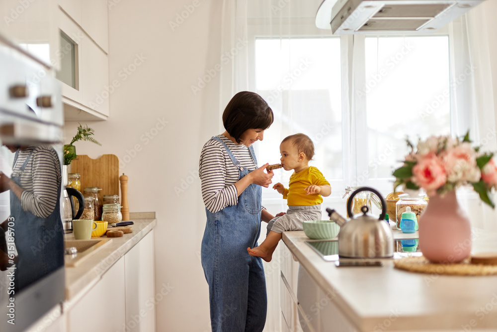 Mother feeding baby boy in the kitchen