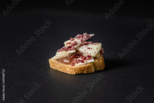 Gastronomic appetizer made cheese, jam, and bread isolated on a black background