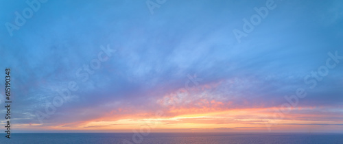 Aerial, panoramic view of the colourful blue, pink and red coloured evening sky over the sea with no obstacles in front. Ideal for sky replacement projects.