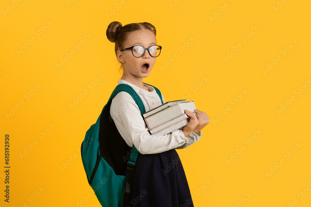 Shocked Cute Little Schoolgirl Wearing Eyeglasses Holding Stack Of Books