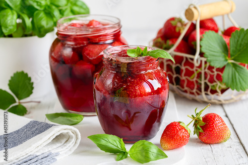 Homemade strawberry jam with basil and whole berries in glass jars. selective focus