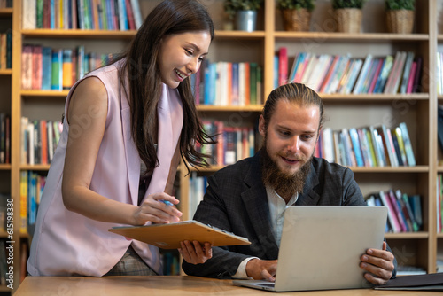 Beautiful woman talking with business man at library. They doing extracurricular work preparing report from university to get highest exam score sits at table with laptop in home office