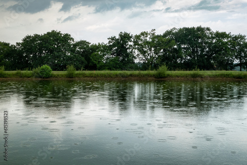 Tableau sur toile Lago com pingos de chuva sobre a água numa tarde cinzenta e nublada de primavera