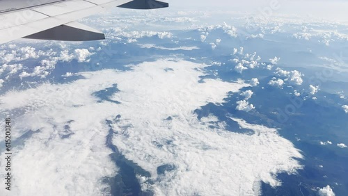 Flight Over The Mountains And Clouds. Detail of an airplane wing flying over clouds in the day